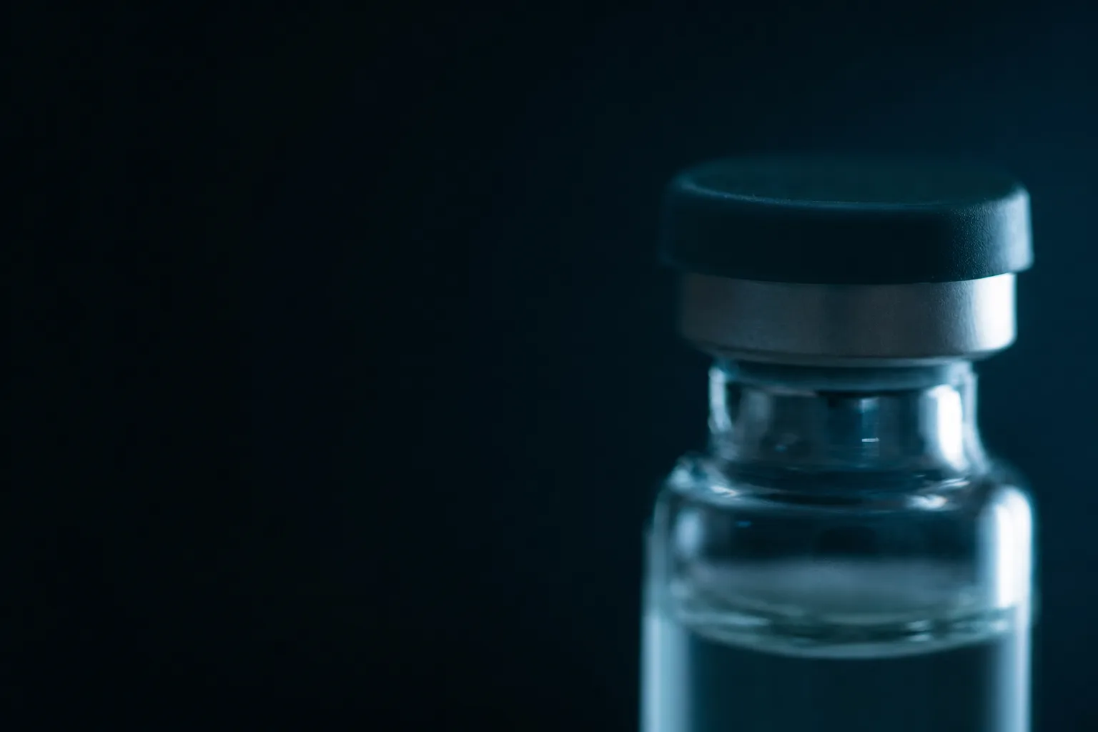 Nine clear glass vials standing in a grid in frost-covered ice.